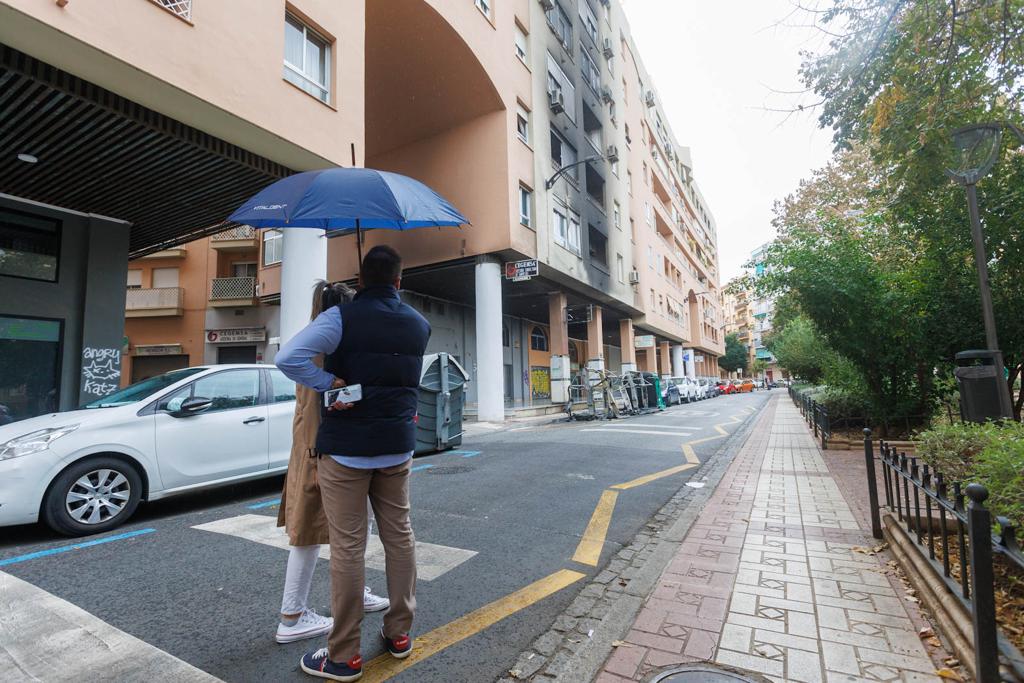 Viandantes observan el hollín que impregna la fachada del edificio.