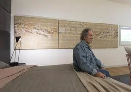El artista Juan Manuel Brazam, en uno de los dormitorios de la Casa Patio del Zaida, con uno de sus trípticos como fondo.
