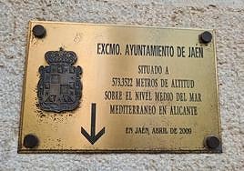 Placa que señala al clavo de nivelación, en la fachada del Ayuntamiento de Jaén.