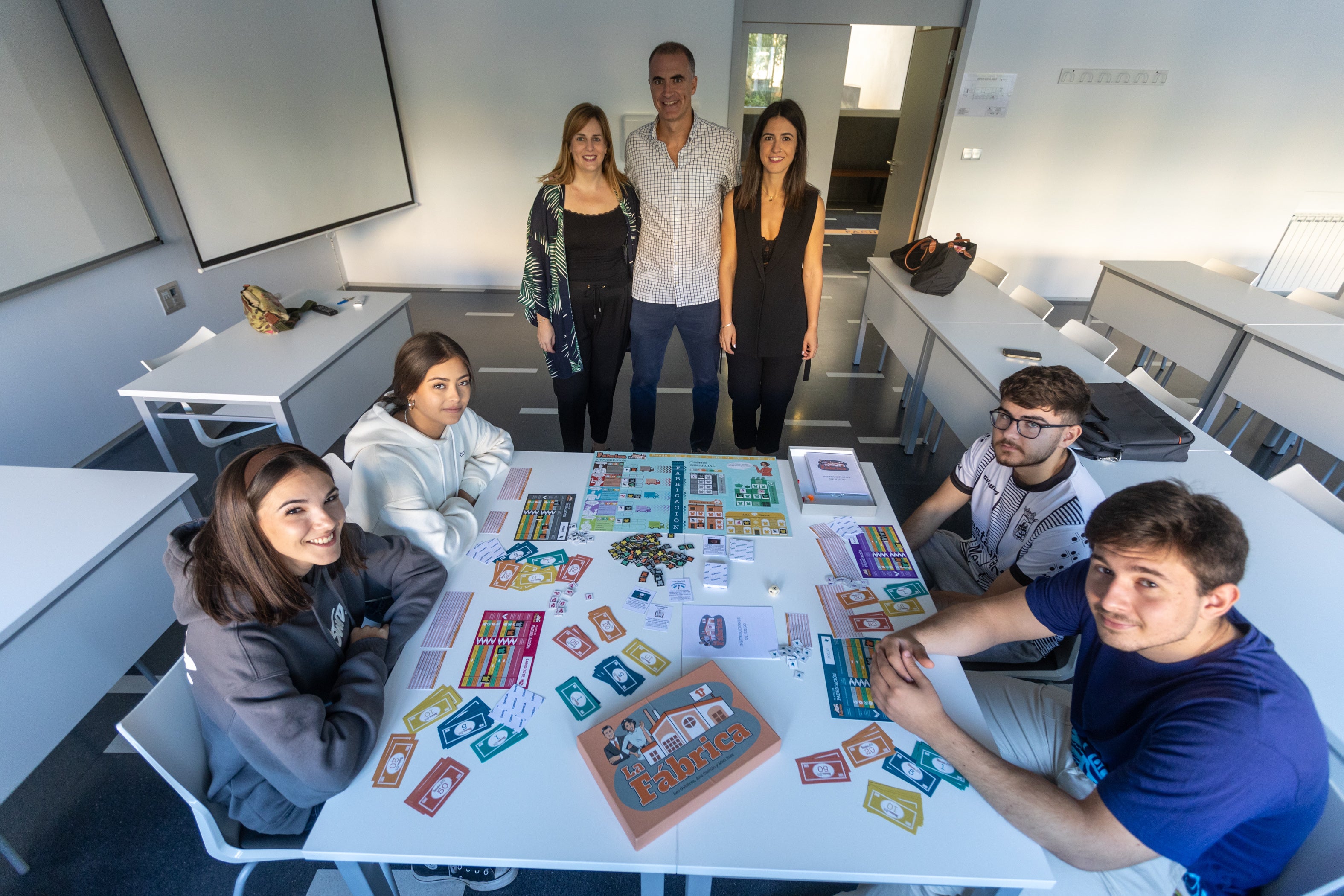 Los profesores, de pie, asisten a una partida del juego entre sus estudiantes.