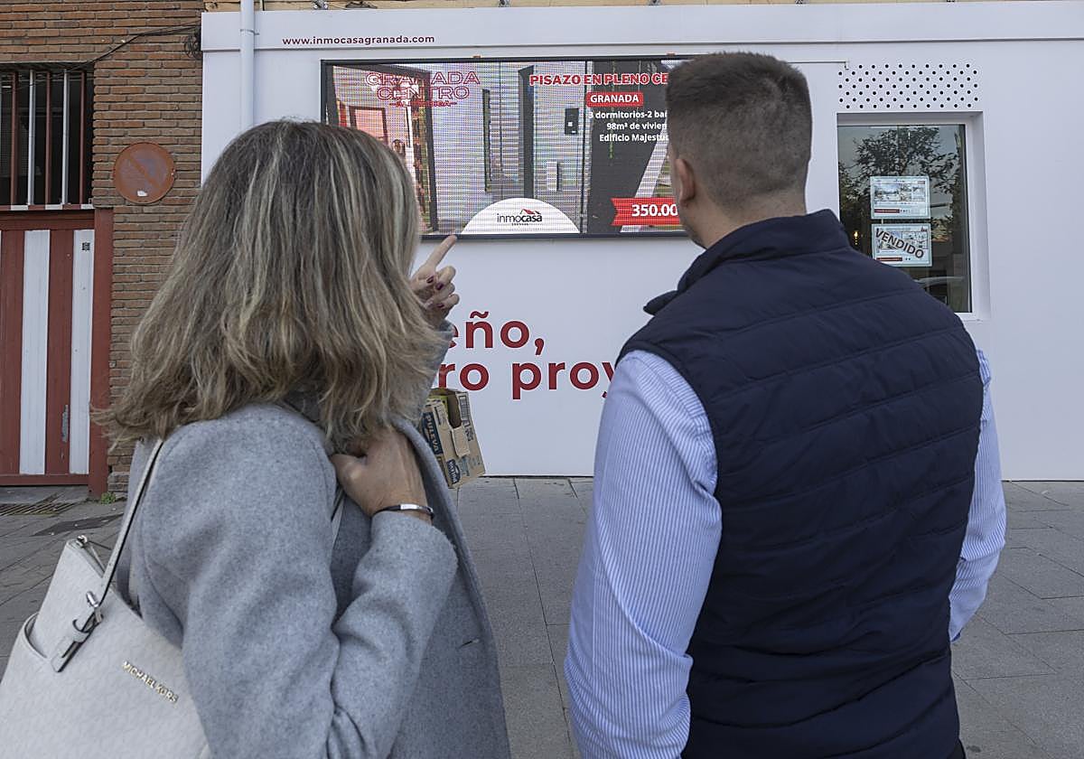Una pareja mira los carteles de una inmobiliaria.