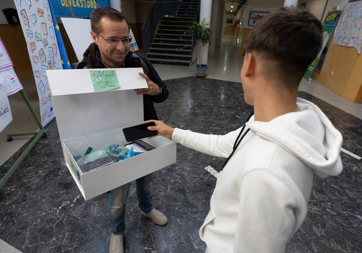 Un alumno del instituto Los Neveros de Huétor Vega deposita su teléfono en la caja donde se quedan 'custodiados'.
