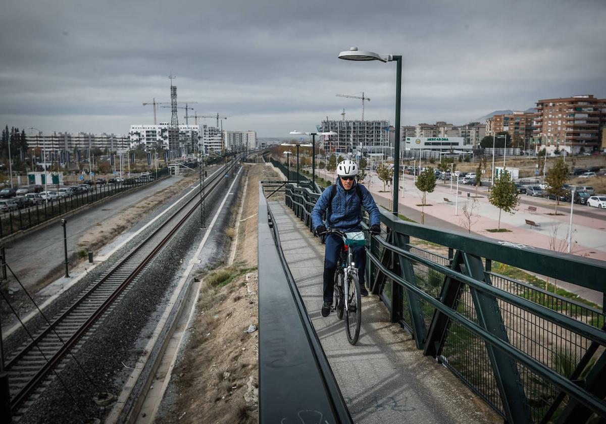 Un hombre pasea en bicicleta junto a las vías del tren.