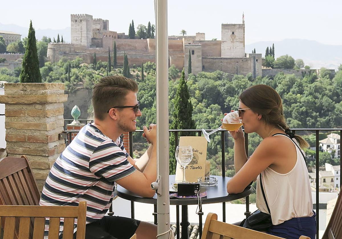 Foto de archivo de turistas tomandp unas bebidas en Granada