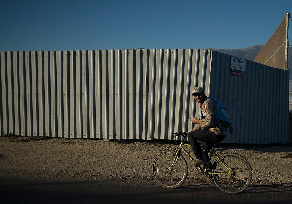 Un trabajador del campo monta en bicicleta entre invernaderos en El Ejido