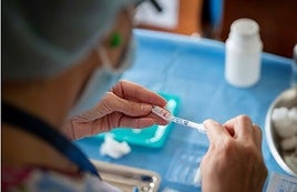 Un sanitario prepara una vacuna.