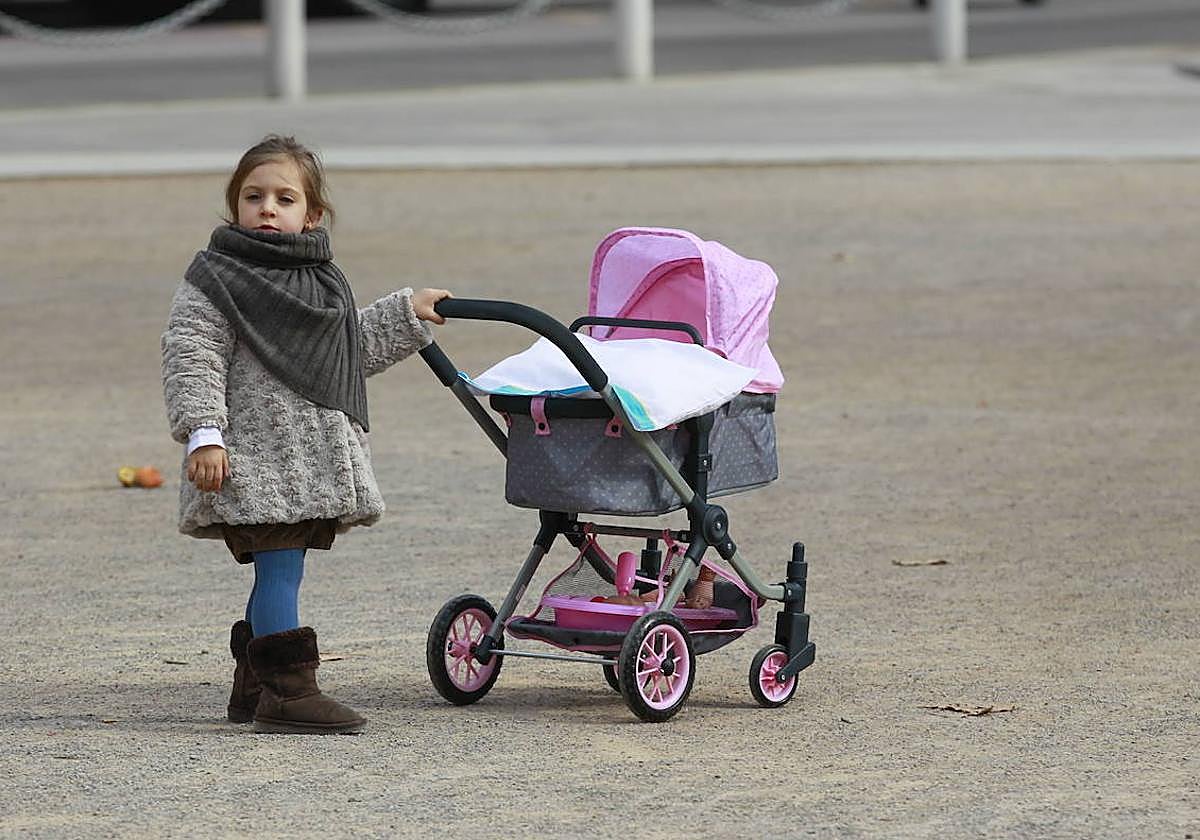 Una niña, con un carrito de bebé en la capital granadina.