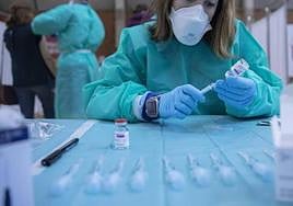 Una sanitaria prepara una vacuna.