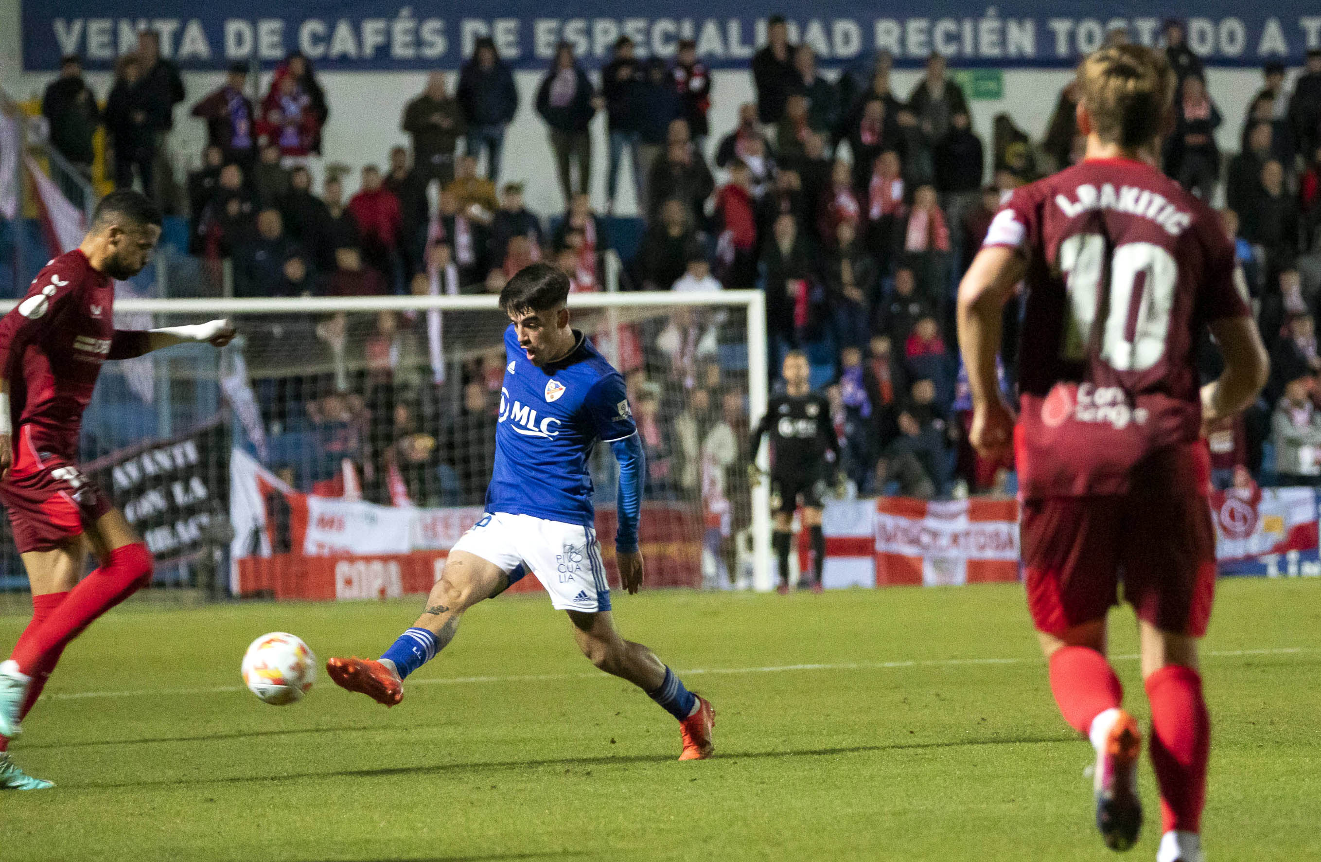 Gelardo abriendo juego para el Linares Deportivo ante la presión del sevillista Nianzou y la mirada del capitán Rakitic. 