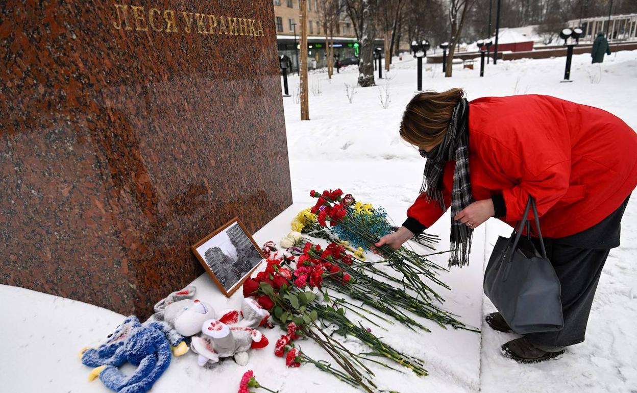 Una mujer deja flores al pie de una estatua para recordar a las víctimas de Dnipró en Moscú
