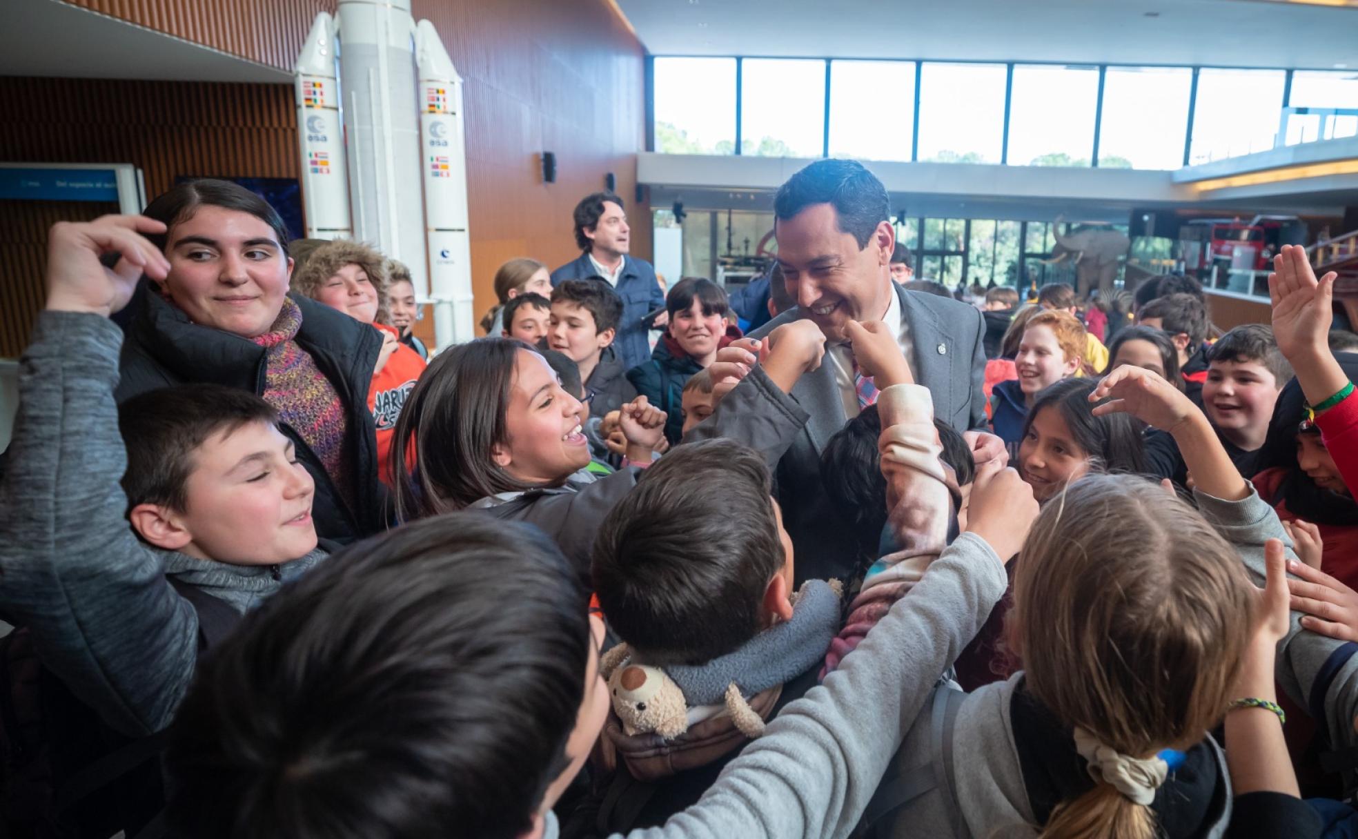 Juanma Moreno, rodeado de alumnos durante su visita al Parque de las Ciencias. 