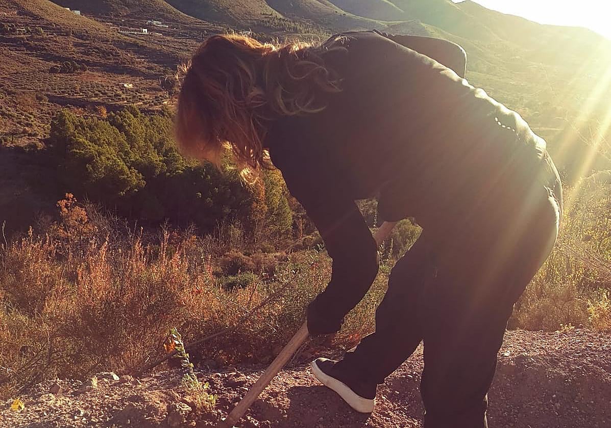 Una mujer planta un árbol en las cercanías de Enix.