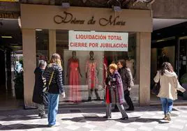 Una tienda con un cartel de liquidación en la calle San Antón, donde la dueña cierra dos comercios de ropa por jubilación sin relevo.