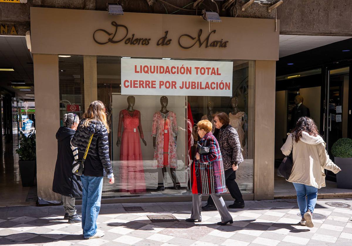 Una tienda con un cartel de liquidación en la calle San Antón, donde la dueña cierra dos comercios de ropa por jubilación sin relevo.