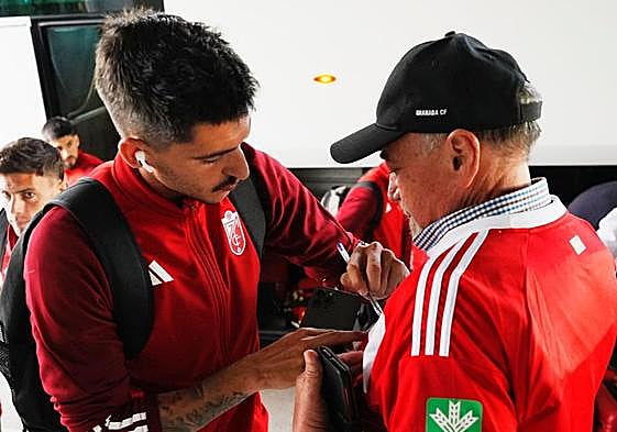 Carlos Neva firma la camiseta a un aficionado a la llegada del Granada a Palma de Mallorca.
