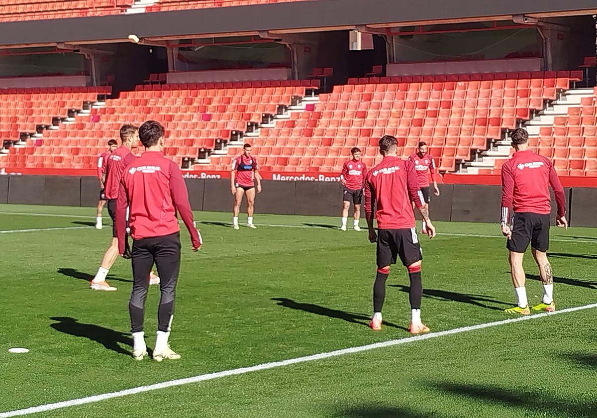 Myrto Uzuni, al fondo a la izquierda, y Lucas Boyé, de espaldas a la derecha, durante los rondos de calentamiento en el entrenamiento del Granada este miércoles en Los Cármenes.