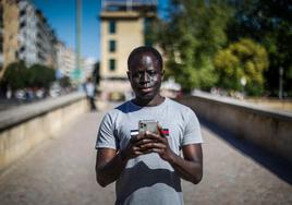 Massene Séne mira su móvil en el puente romano.