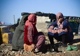 Varias mujeres esperan a unos voluntarios de Cruz Roja, en el municipio almeriense de Níjar, que atienden a diario a los miles de inmigrantes que residen en asentamientos chabolistas.
