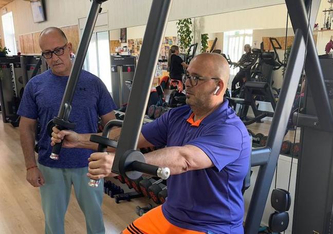 José junto a Juan practicando las repeticiones en el gimnasio