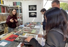 Una mujer se interesa por un libro en una de las casetas.