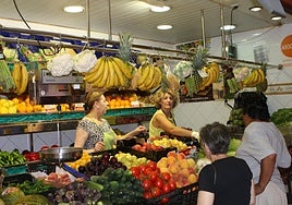 Clientes comprando en un puesto de fruta y verdura, de archivo.