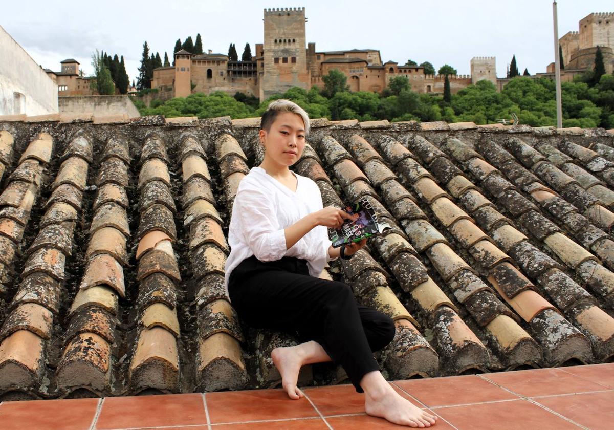 Wakana Sakamoto, en la terraza de su casa, con un ejemplar de 'Hero Mask' y vistas a la Alhambra.