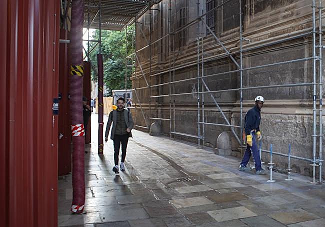 Viandantes transitan por debajo de la estructura de protección eventual.