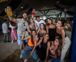 Un grupo de chavales levantan sus jarras de colores en la caseta La Mona.