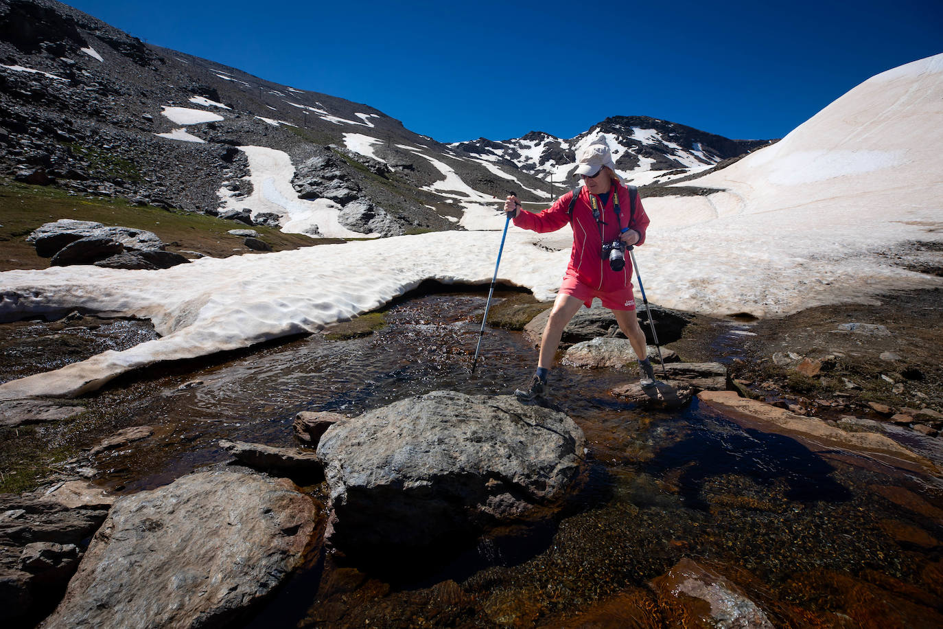 Una senderista camina por un arroyo del deshielo en Sierra Nevada.