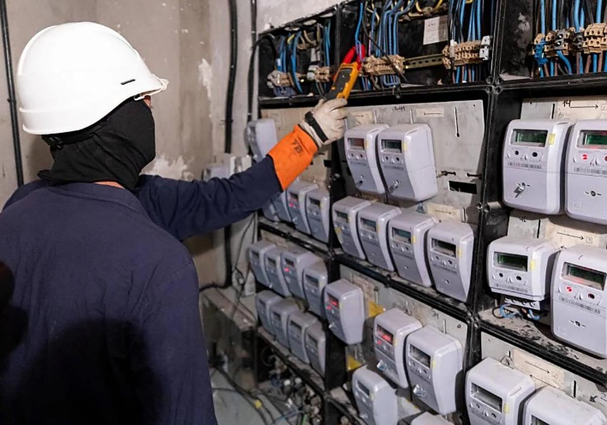 Dos técnicos de Endesa comprueban si hay fraude en un cuarto de contadores en un bloque de viviendas de Granada