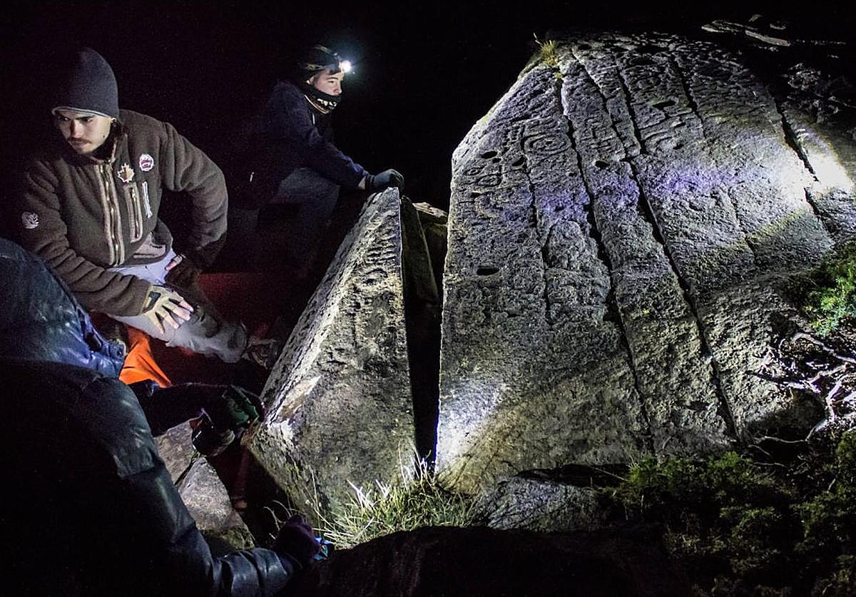 Investigadores, provistos de frontales, analizan el impresionante petroglifo hallado en Sierra Nevada.