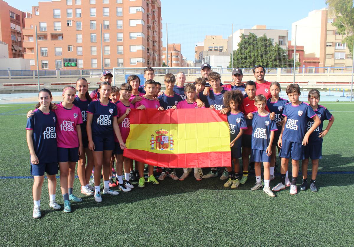 Jóvenes del Campus de Verano EDA posan con la bandera de España en el Estadio de la Juventud 'Emilio Campra'.