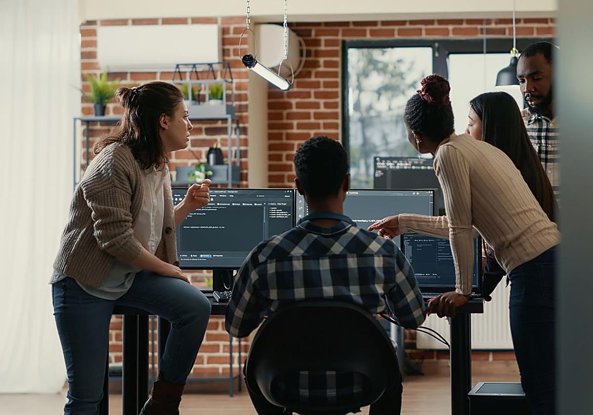 Un grupo de personas observa pantallas con código.