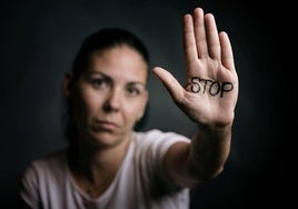 Imagen de archivo de una mujer mostrando la mano con la palabra 'Stop' escrita en ella.