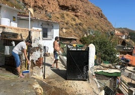 Vecinos de Beas de Guadix limpian las puertas de sus viviendas.