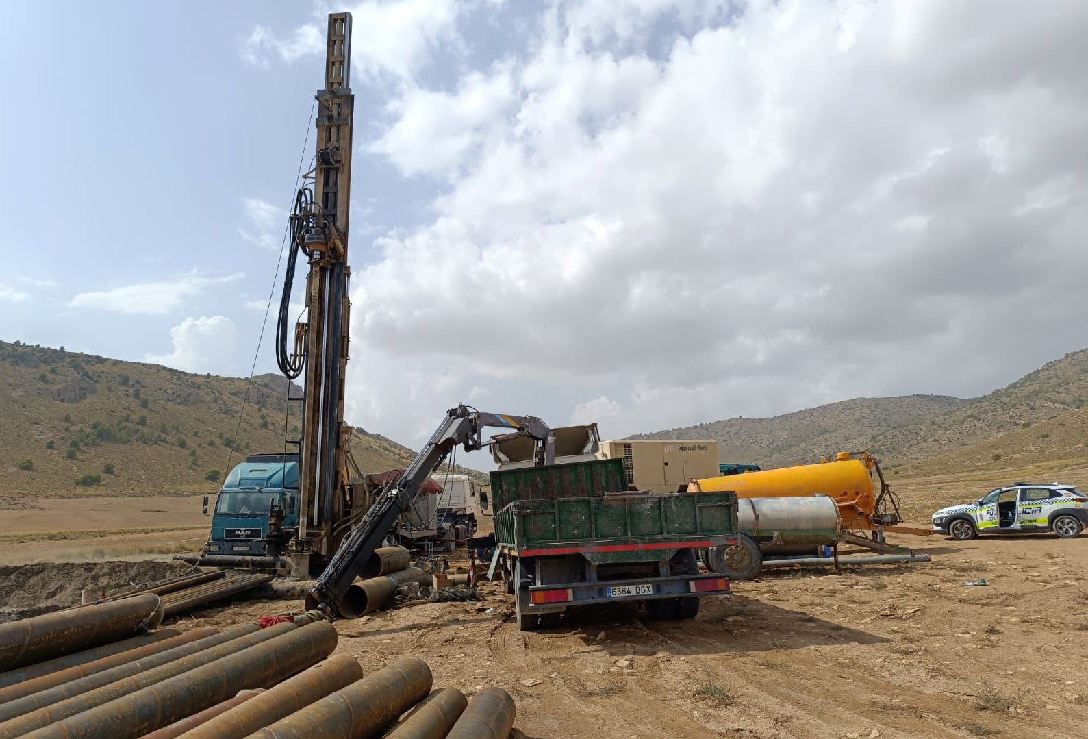 Maquinaria, tuberías y camiones en el lugar del sondeo.