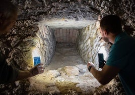 Manuel Moreno y Antonio Manuel Montufo iluminan con sus teléfonos móviles uno de los diez tragaluces que daban claridad al corredor y la sala cuadrada del criptopórtico de Las Gabias.