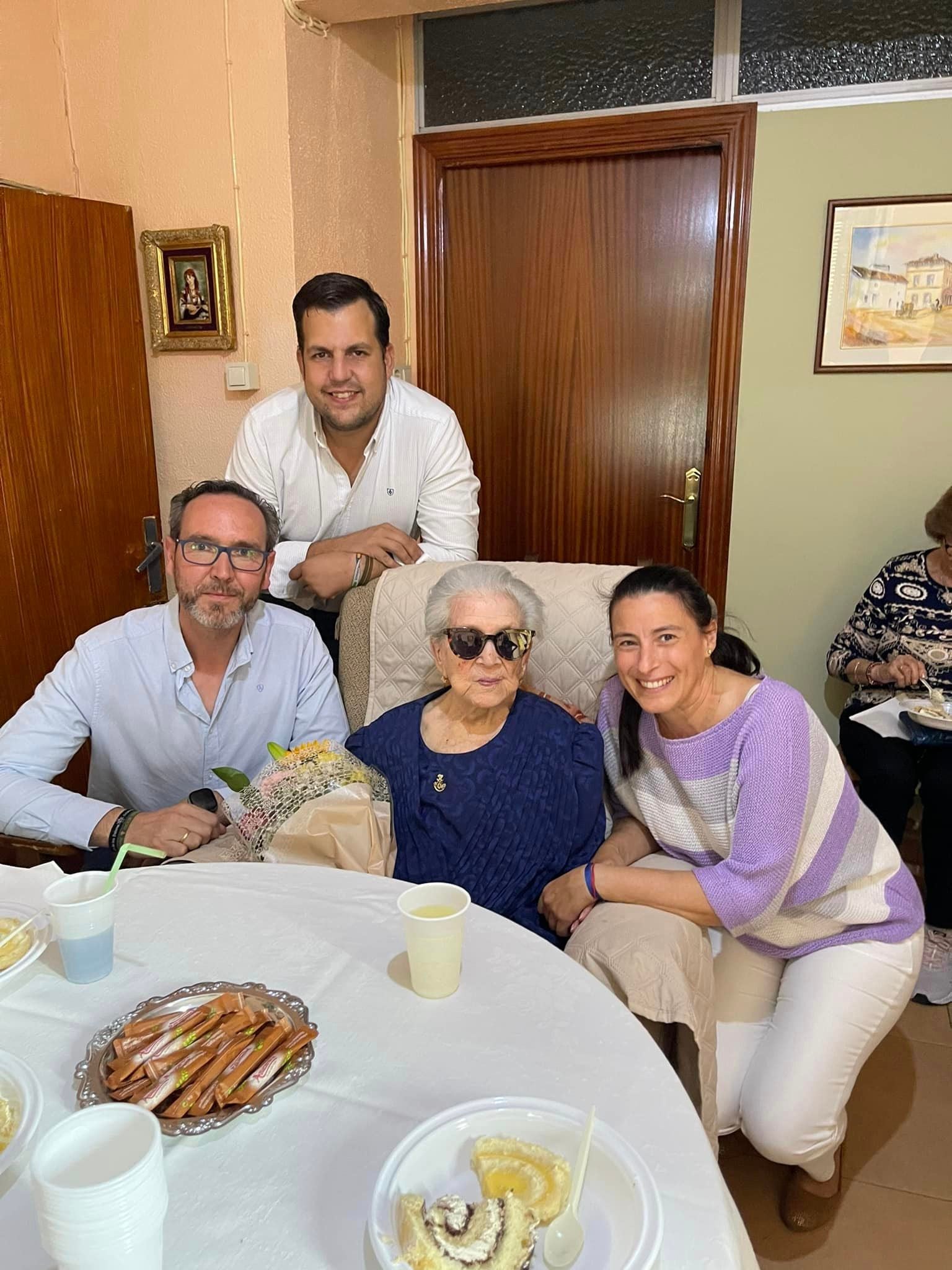 María, 104 años, junto a representantes municipales que la visitaron y regalaron un ramo de flores.