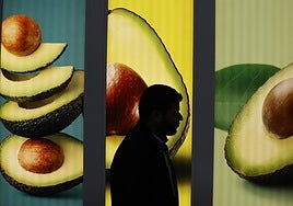 Un visitante pasa frente a un cartel de aguacates, uno de los productos estrella de la feria Fruit Attraction.