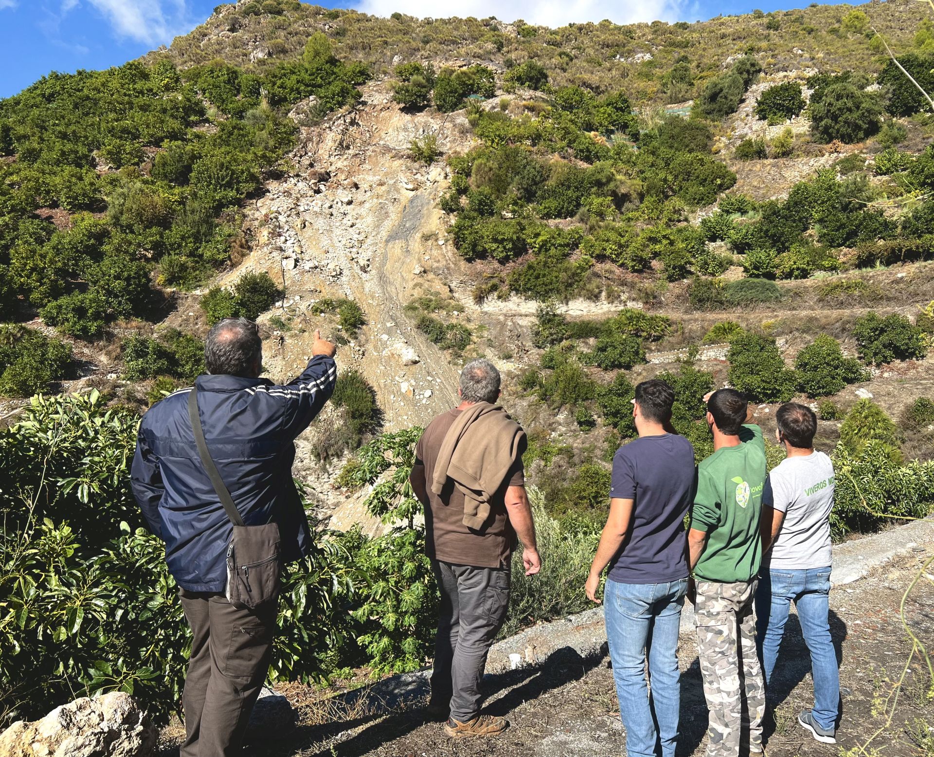 Los agricultores miran el derrumbamiento que corta el camino de acceso a sus fincas.