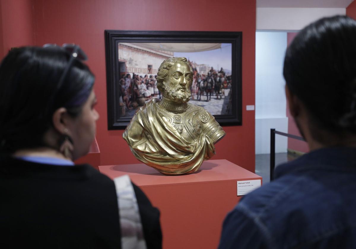 Personas observan un busto de Hernán Cortés en una exposición en México.