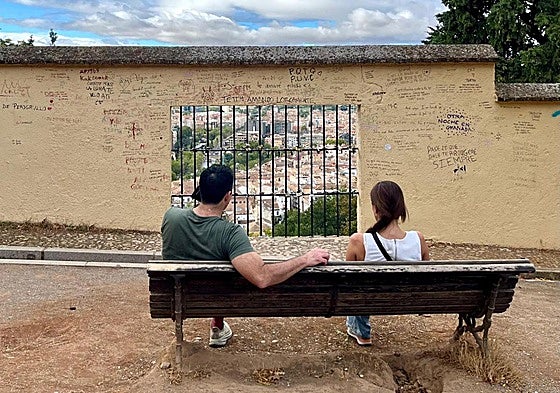 Dos turistas con cara de llamarse James y Alison, embelesados con el muro de las frasecitas ñoñas.