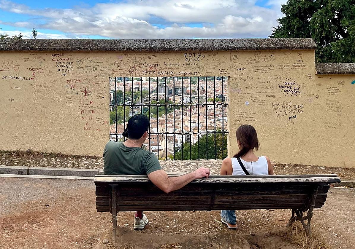 Dos turistas con cara de llamarse James y Alison, embelesados con el muro de las frasecitas ñoñas.