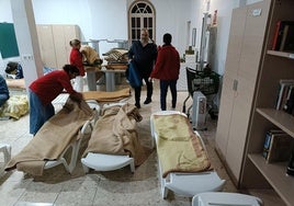 El director, el conserje y las dos trabajadoras sociales de la Casa de Cogida Madre de Dios preparan las mantas en las hamacas.