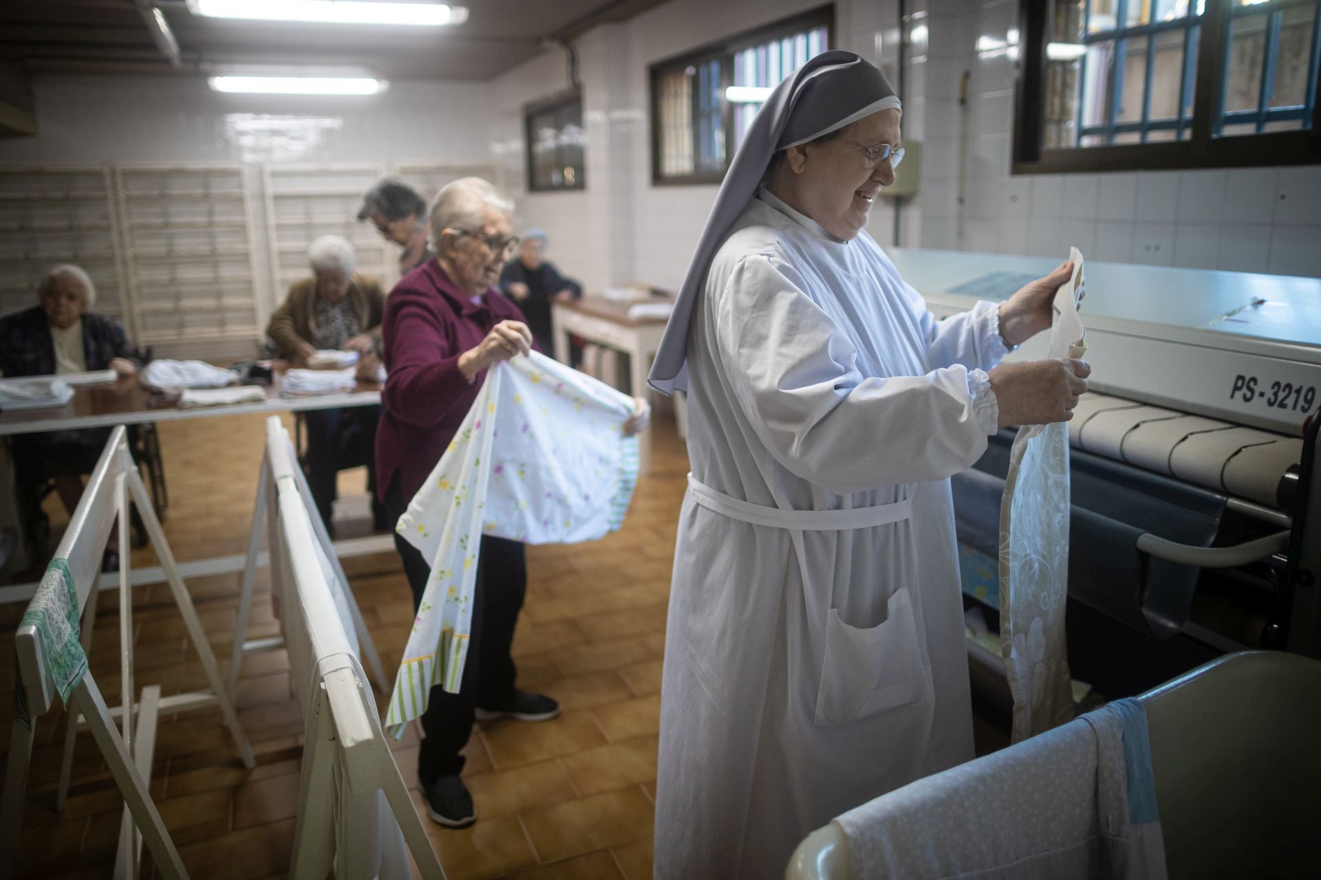 Una de las hermanitas trabajando en la lavandería junto a las residentes que pueden ayudar.