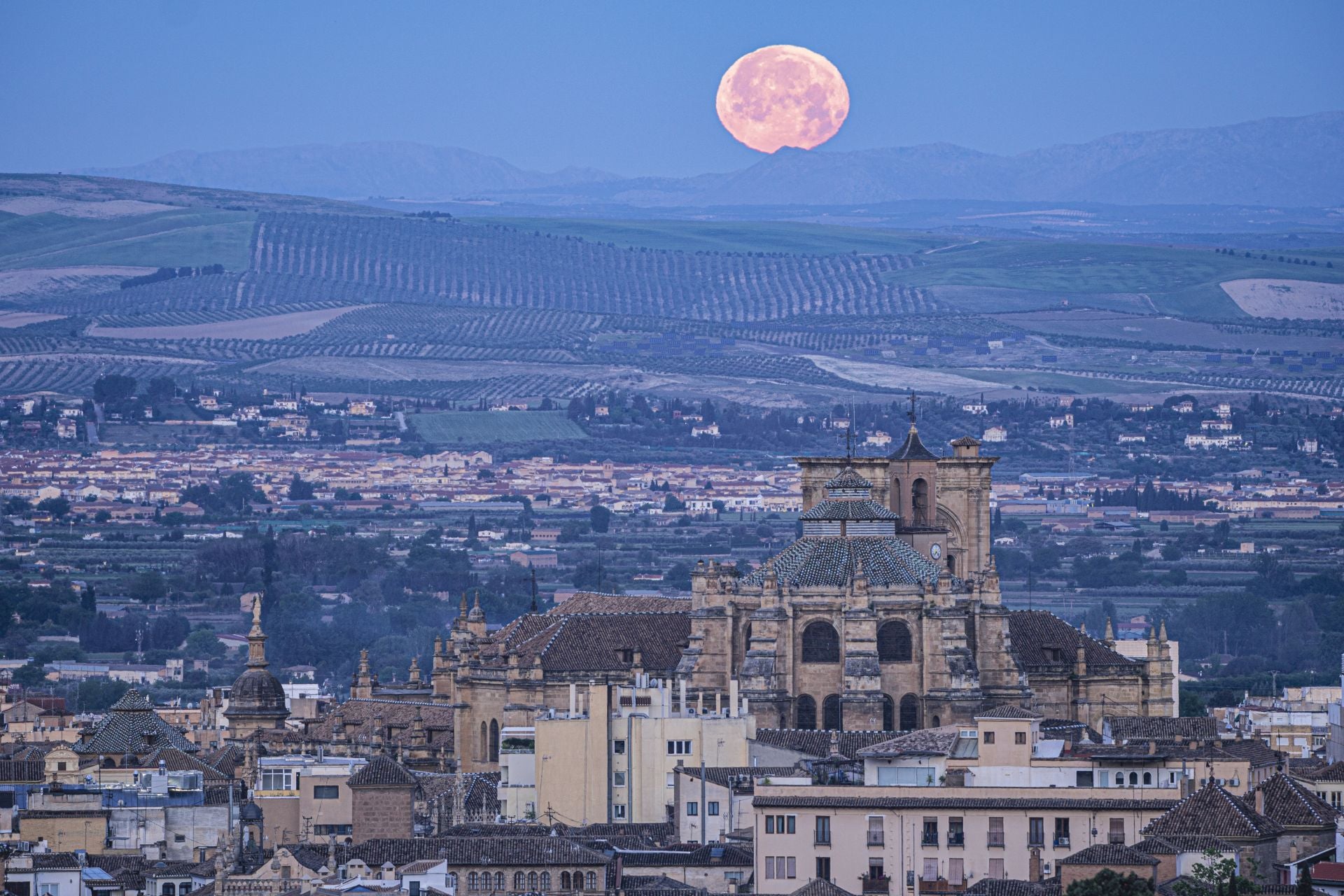 Fotografía de la Catedral de Granada con la Luna asomando por la Vega.