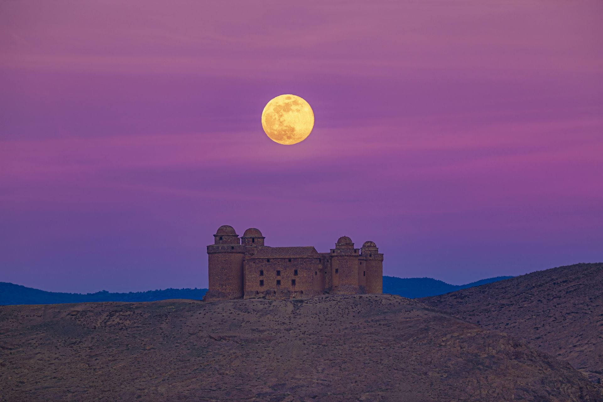 El Castillo de la Calahorra, una de las joyas patrimoniales de la provincia de Granada, bajo la Luna llena con tonos amarillentos.