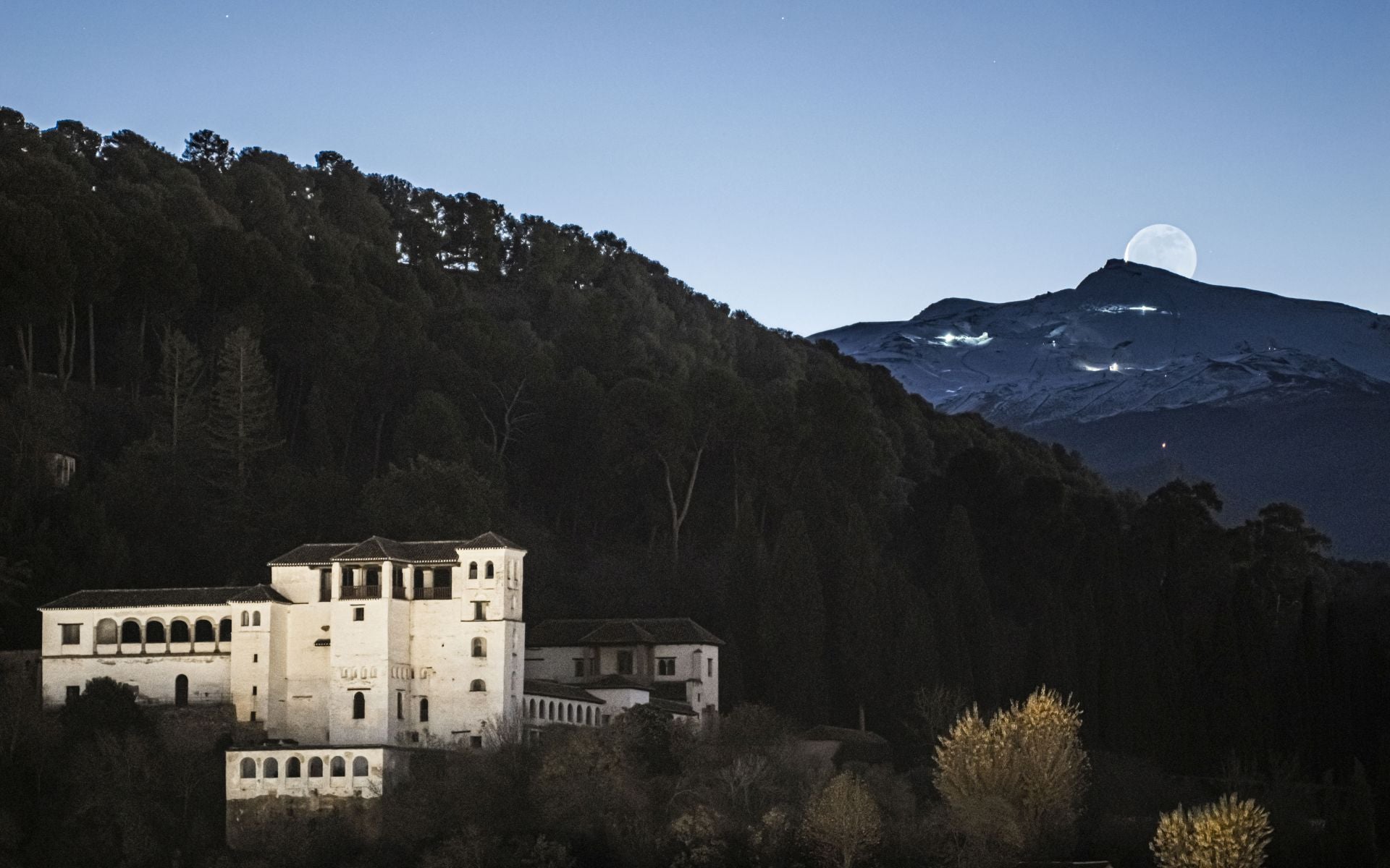 La Luna llena despunta sobre Sierra Nevada con el blanco Generalife en primero plano.