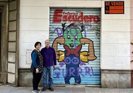 Juanamari y Manuel Escudero, frente a la persiana de su frutería, con su peculiar mascota.