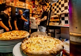 Uno de los cocineros del restaurante sacando una pizza del horno.